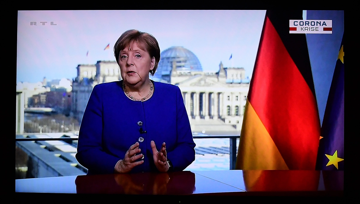 Angela Merkel during her TV address, next to her the German flag. picture alliance/dpa/Revierfoto | Revierfoto