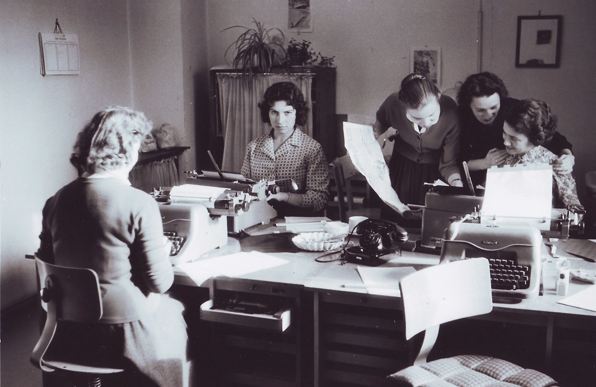 Black and white photo of women working at desks and typewriters