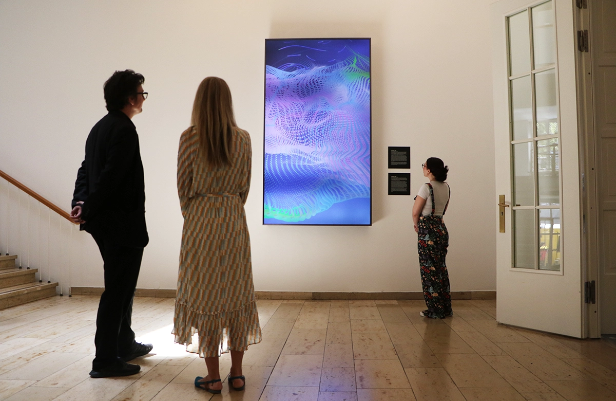 Viewers in front of a screen showing the forms of the data artwork. 