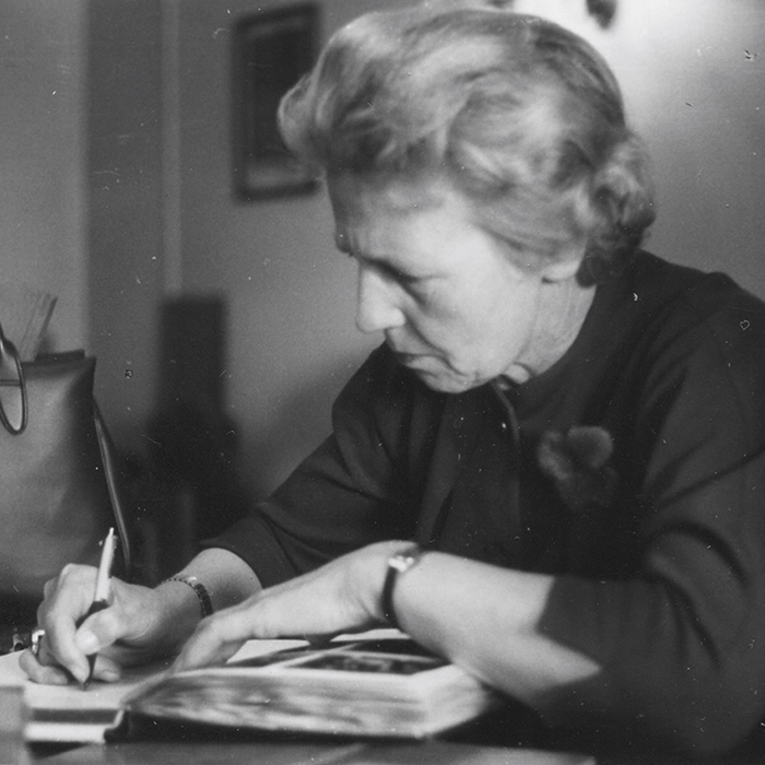 Hildegard Harlander with book and pen at her desk.